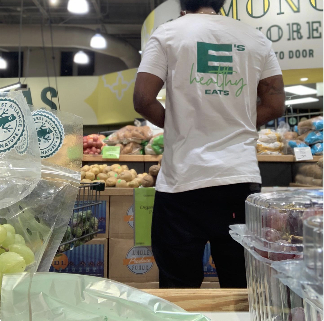 Team member in an E's Healthy Eats tee shopping fresh produce