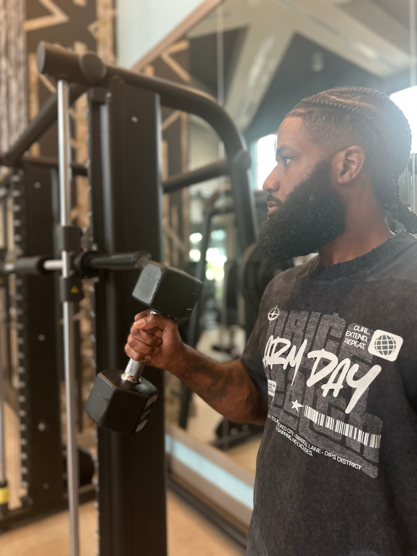Man in the gym wearing the Arm Day tee while curling a dumbbell