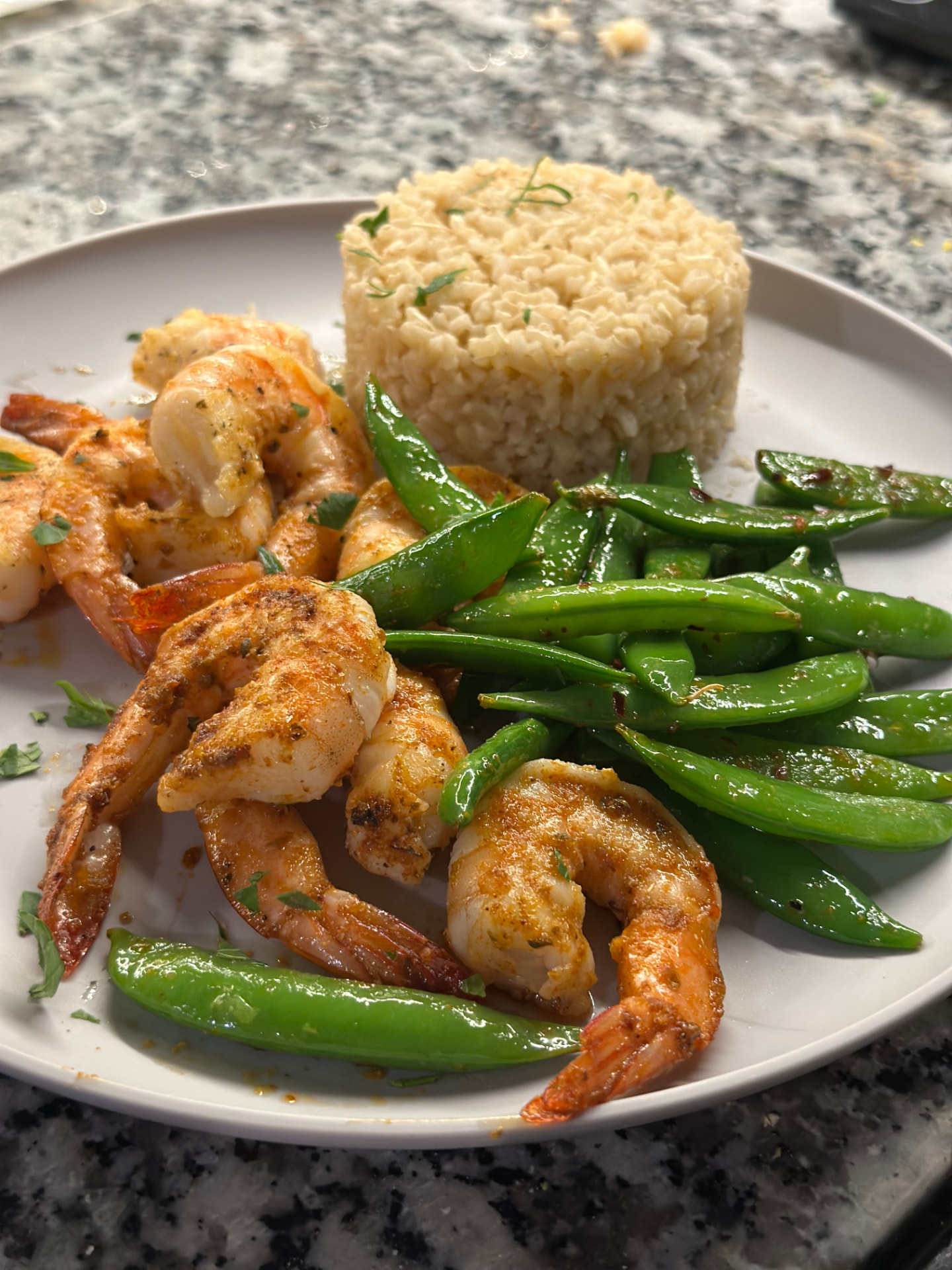 A plate of grilled shrimp with peas and brown rice
