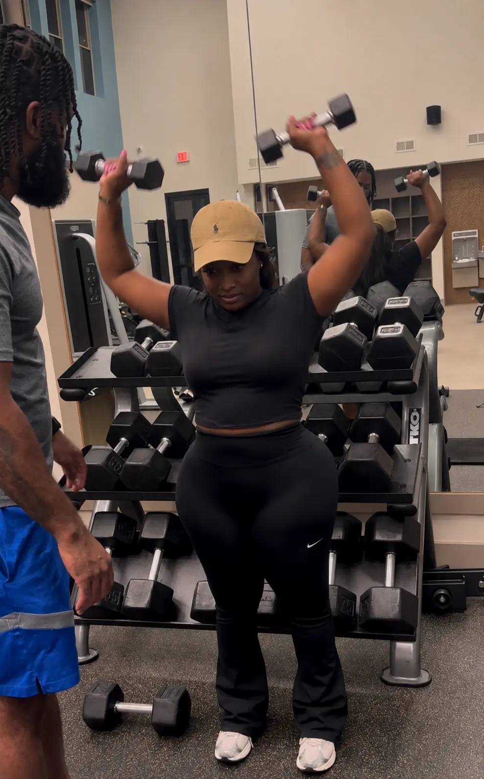 A Price of Health coach guiding a client through a dumbbell press