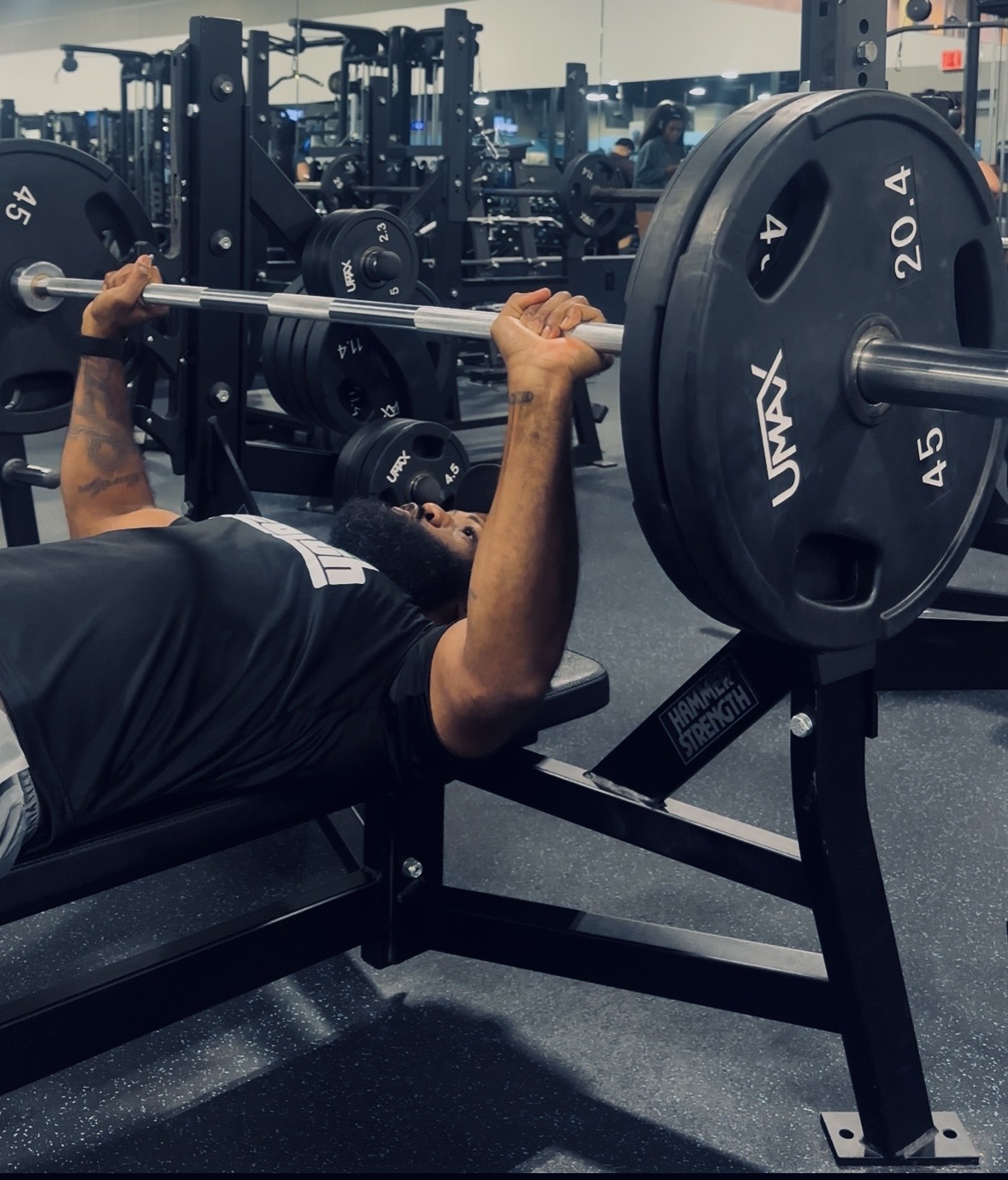 A Price of Health athlete pressing a loaded barbell on the bench