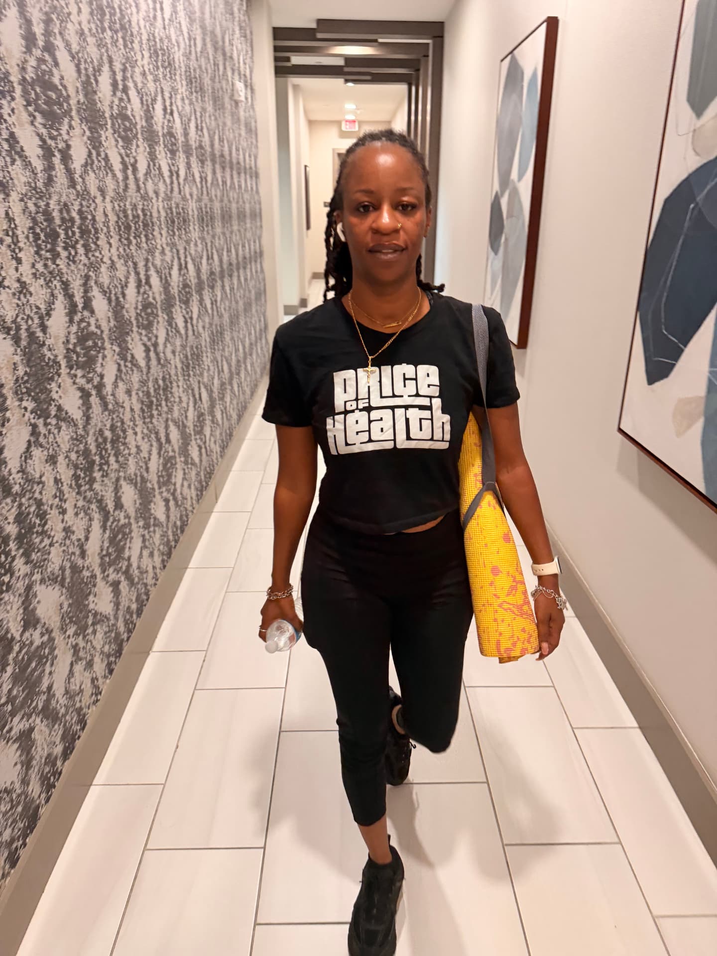 Woman carrying a yoga mat while wearing a Price of Health tee