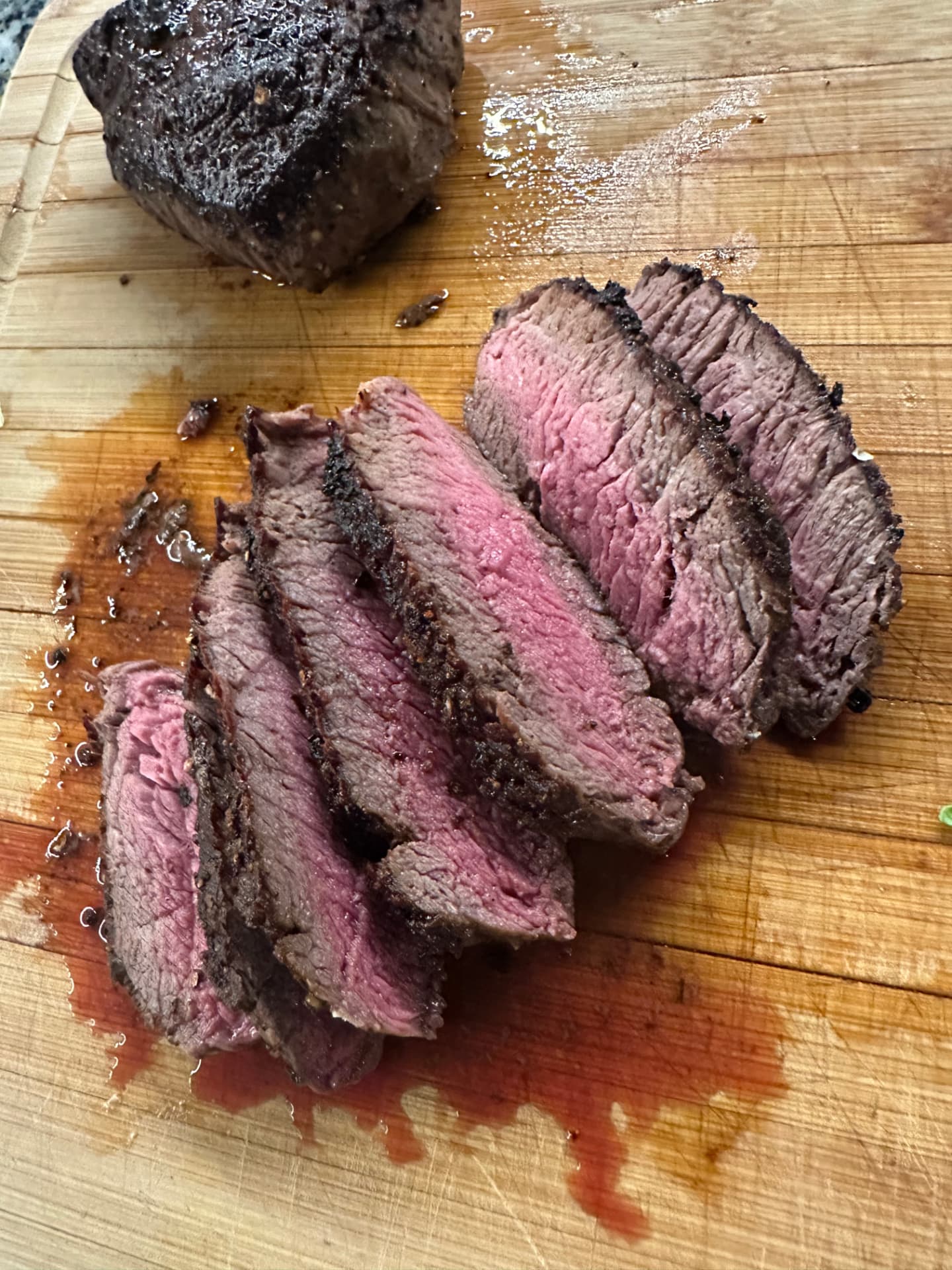 Sliced steak resting on a wooden cutting board