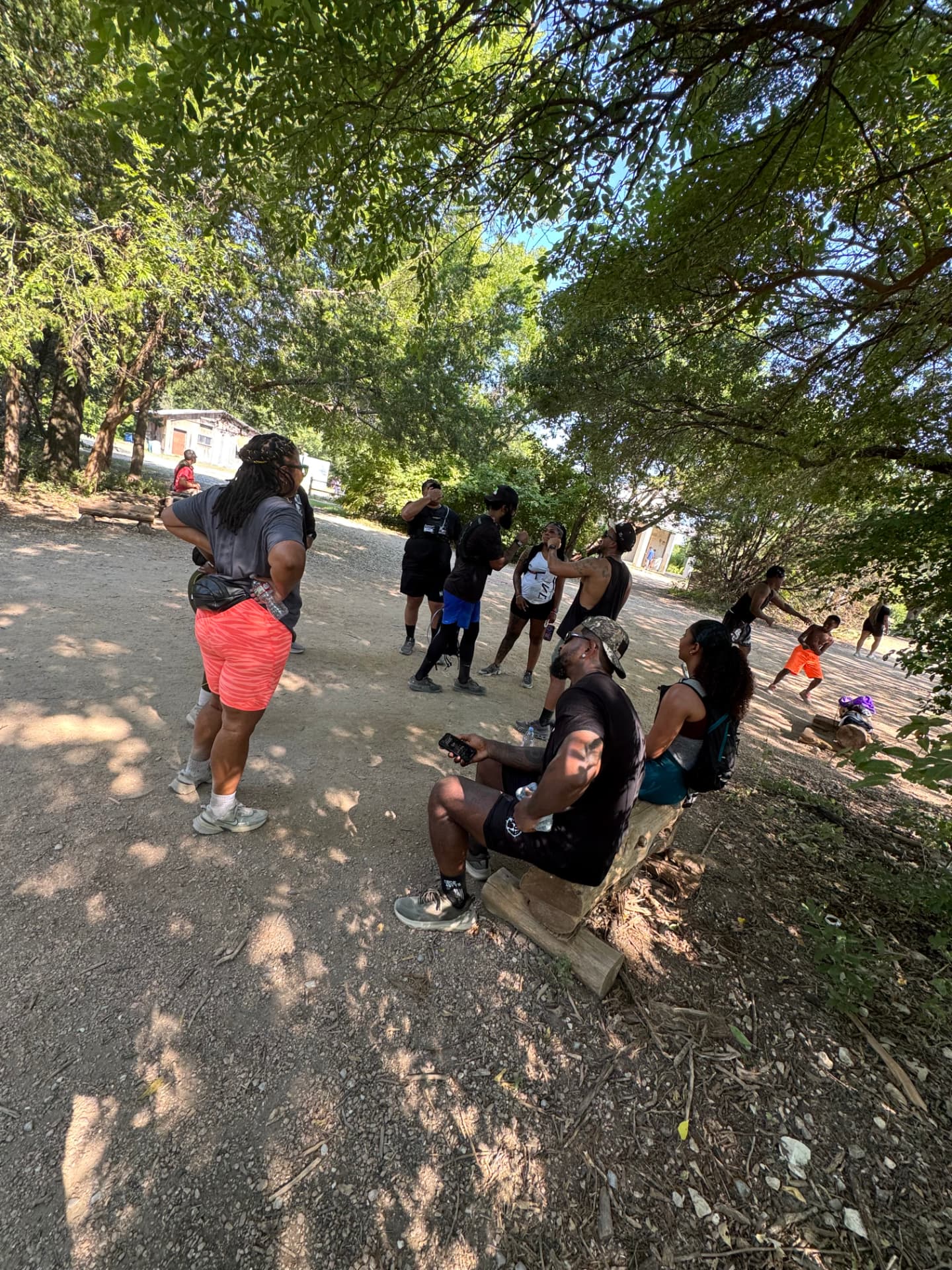 A community group gathered along a shaded trail during a hike