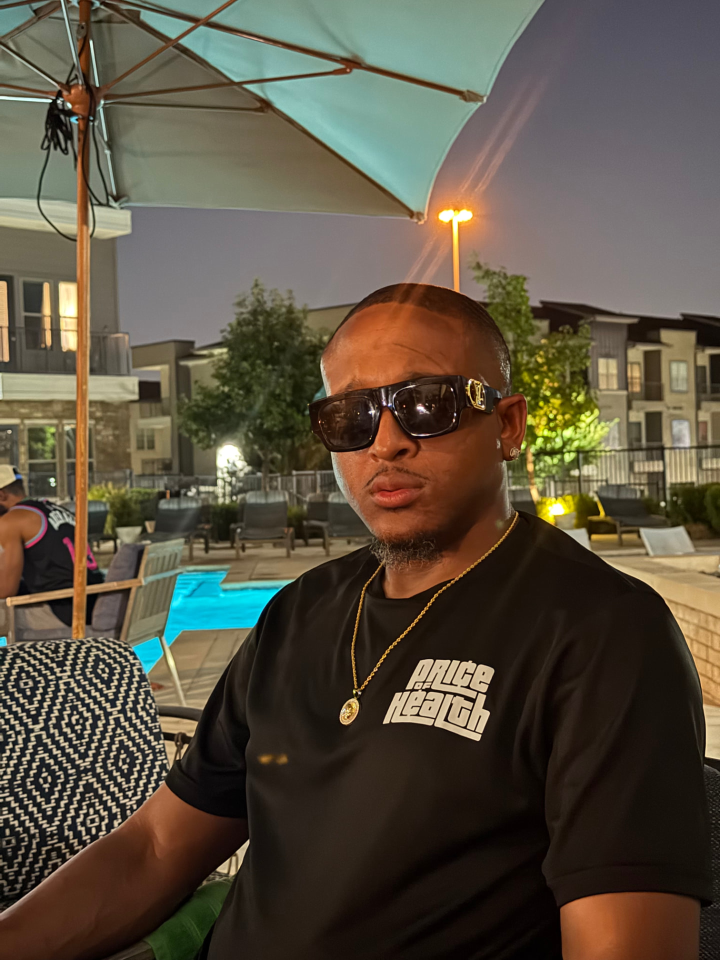 Man poolside wearing a Price of Health tee
